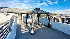 A covered outdoor seating area with a metal roof and striped curtains, adjacent to a building with a white exterior and a metal railing. - Perfect Inn Motel (Las Vegas)