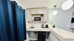A compact kitchen with a microwave, sink, and coffee maker. - Perfect Inn Motel (Las Vegas)