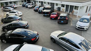 A parking lot with multiple cars and a building with numbered doors in the background. - Perfect Inn Motel (Las Vegas)