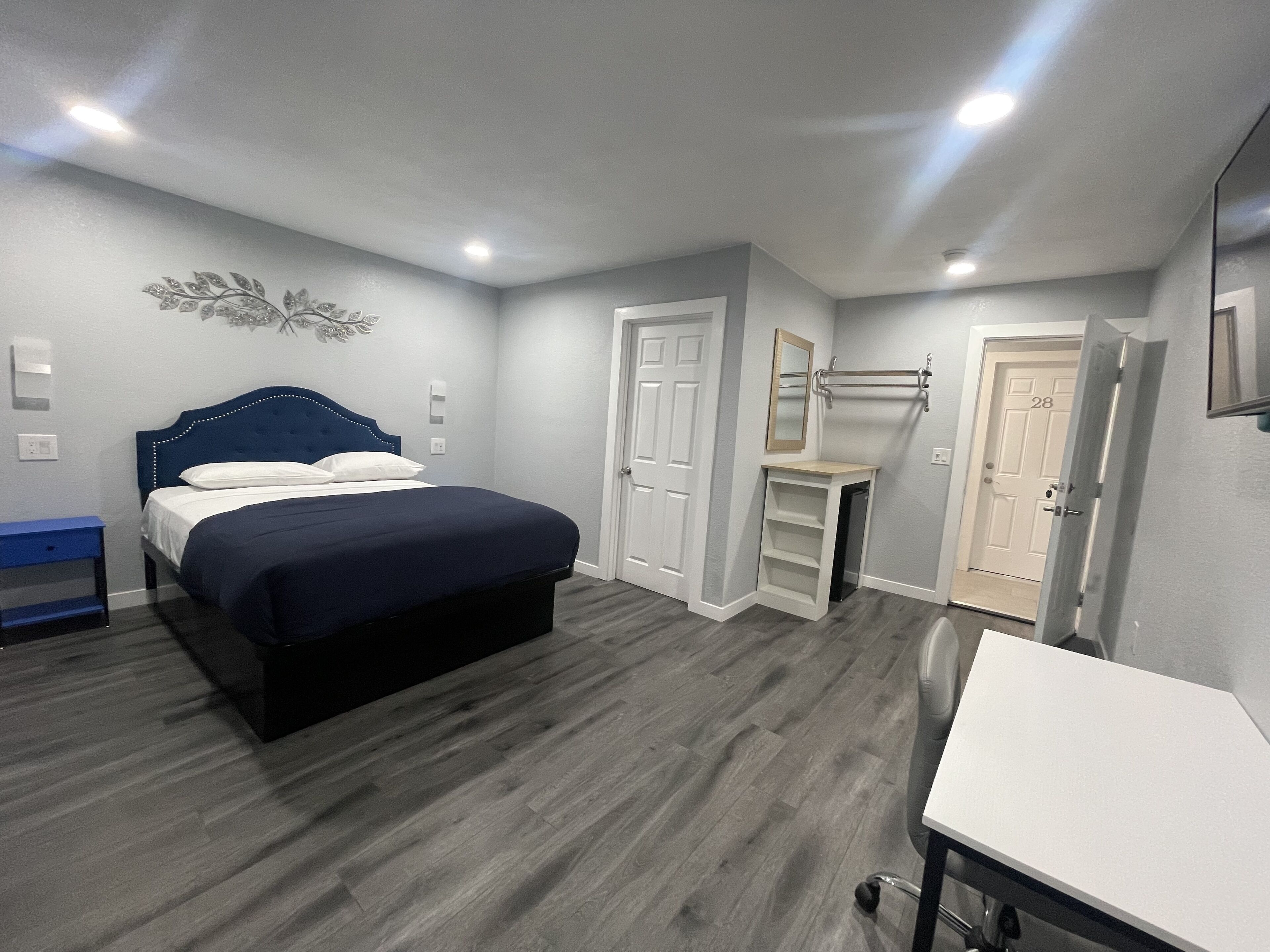 A bedroom with a bed, bedside table, wardrobe, and a desk.