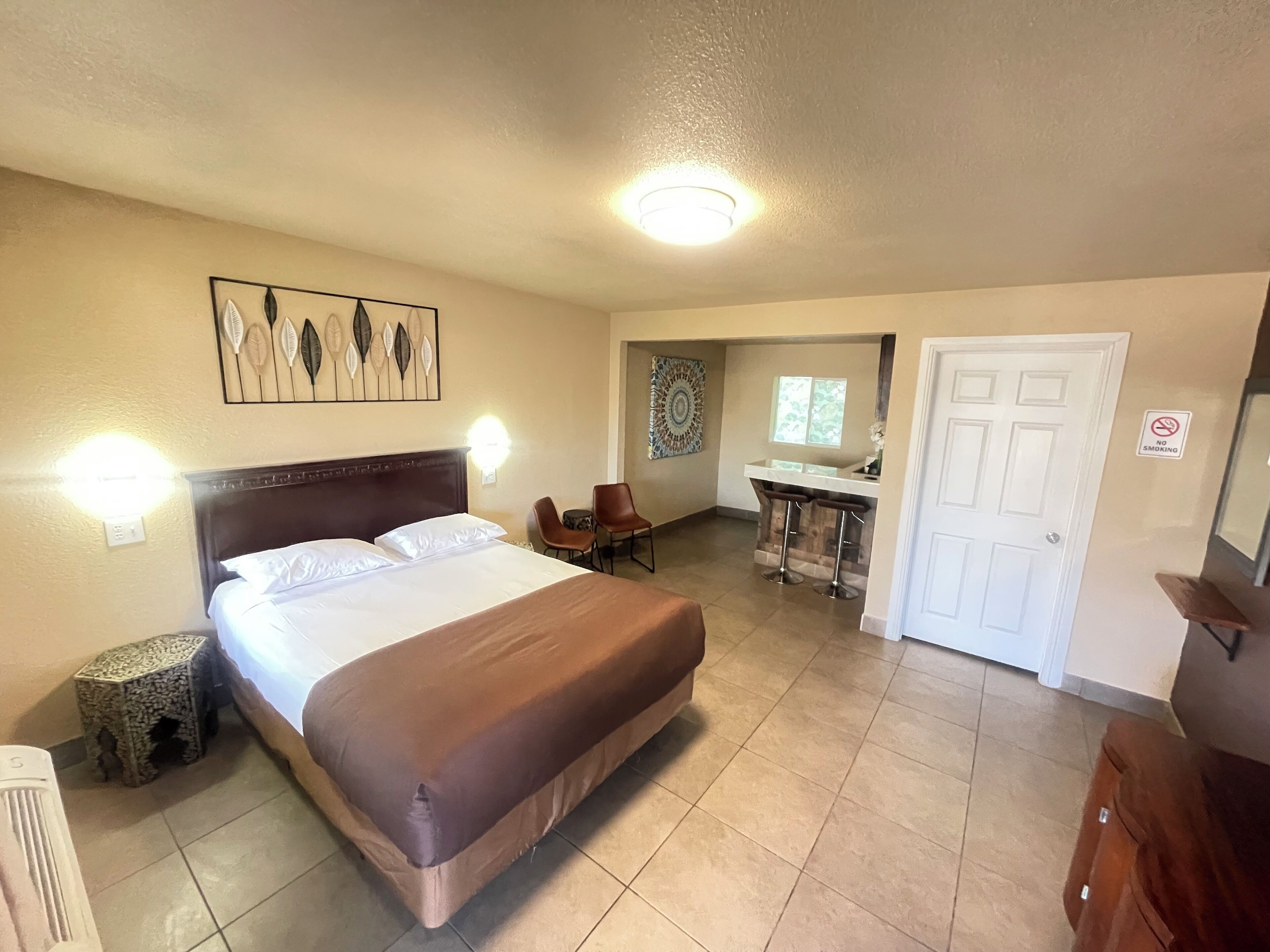 A hotel room with a large bed, a desk, a chair, and a bathroom.