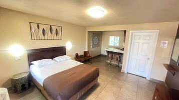 A hotel room with a large bed, a desk, a chair, and a bathroom.