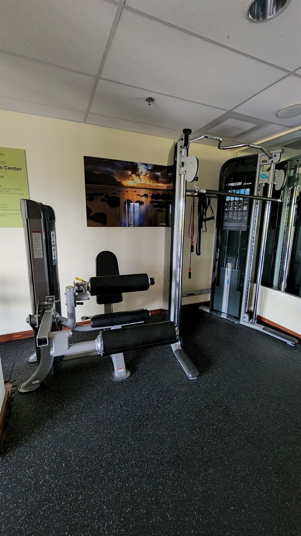 A gym with exercise equipment, a wall-mounted picture, and a sign on the wall.