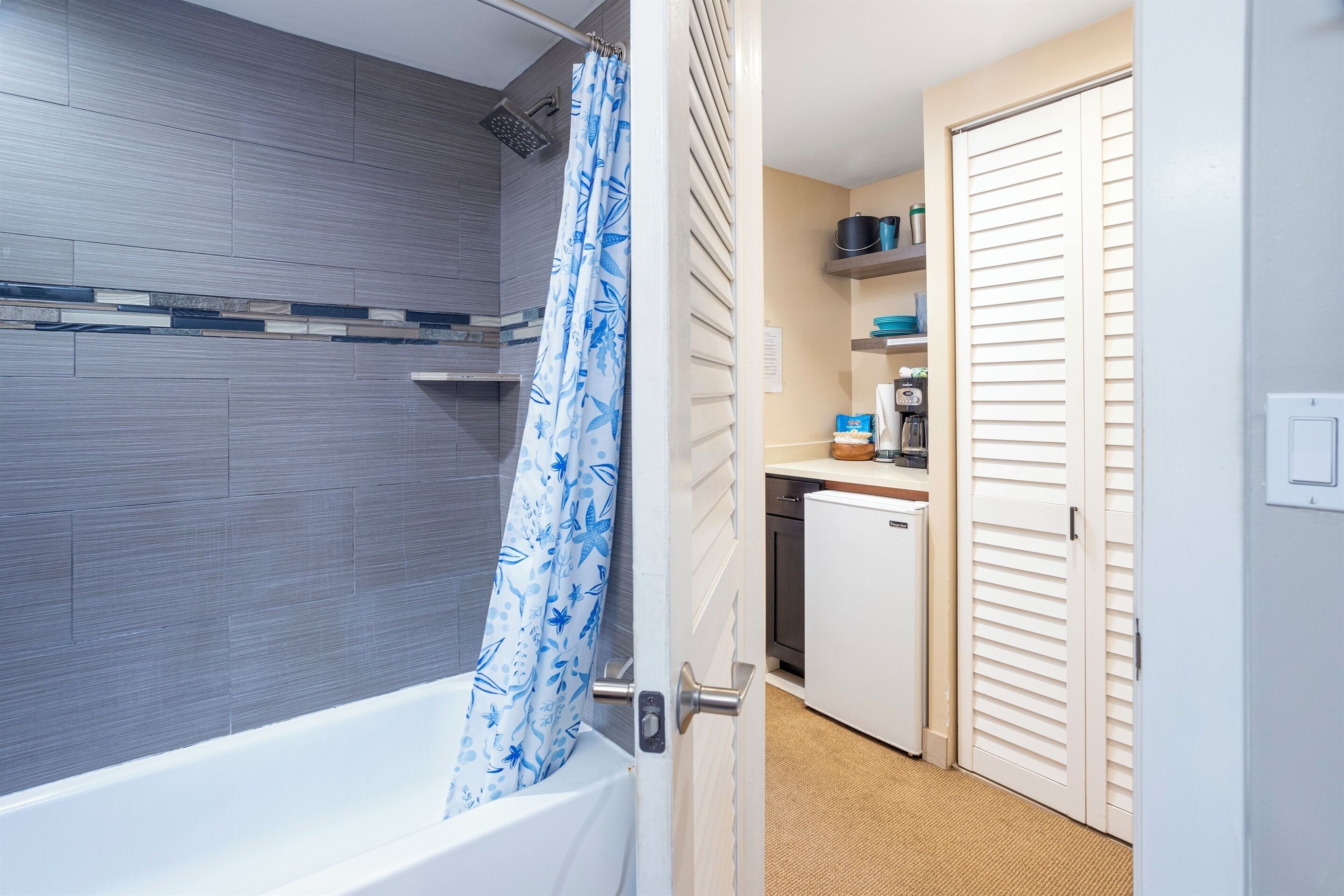 A bathroom with a bathtub, shower, and a curtain with a leaf pattern.