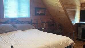 A bedroom with a bed, wooden ceiling, a window with blinds, a framed picture on the wall, and a fireplace. - Family Fun Villa - Very Clean (Warrens)