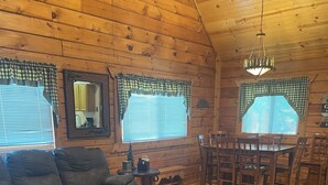 A cozy cabin interior with a wooden ceiling, a dining table with chairs, a sofa, and a small Christmas tree. - Family Fun Villa - Very Clean (Warrens)