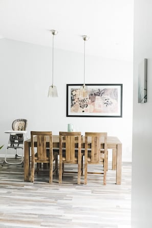 A dining area with a wooden table and chairs, a high chair, and a framed abstract painting on the wall. - Waterfront Boca Raton Home - Pets OK - Heated Pool (Boca Raton)