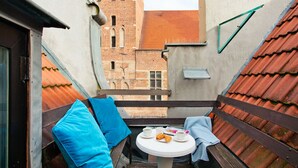 Un petit balcon avec une table, deux chaises et une vue sur un immeuble en briques.