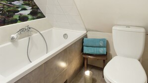 Une salle de bain avec une baignoire, des toilettes et un petit tabouret.