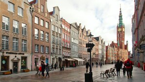 Une rue historique européenne, caractérisée par son architecture traditionnelle, une tour de l’horloge remarquable et un café Starbucks.