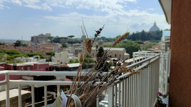 Ein Balkon mit Blick auf eine Stadtlandschaft, darunter Gebäude und eine Kuppel in der Ferne.