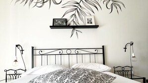 Ein Schlafzimmer mit einem Bett, einem an der Wand befestigten Regal mit gerahmten Bildern und zwei Nachttischen mit Lampen.