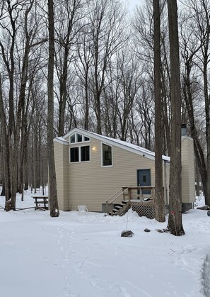 A small, single-story cabin with a covered porch and a staircase leading to the entrance.