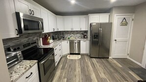 A kitchen with white cabinets, stainless steel appliances, and a wooden floor. - Cozy, Relaxing, Getaway house in Big Bass community Poconos-3 mins walk to lake (Gouldsboro)