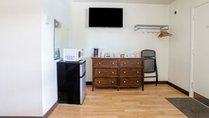 A compact room with a flat-screen TV mounted on the wall, a wooden dresser, a microwave, and a small refrigerator. - Cadiz Motel by OYO on Route 250 (Cadiz)