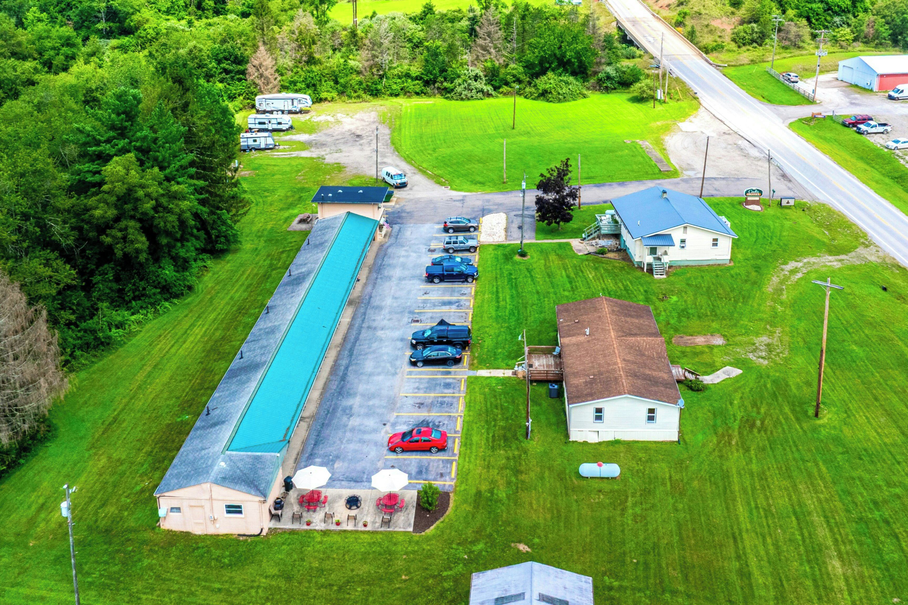 Vue aérienne d’un terrain de camping avec des camping-cars, une piscine et un petit bâtiment doté d’un espace extérieur aménagé pour s’asseoir.