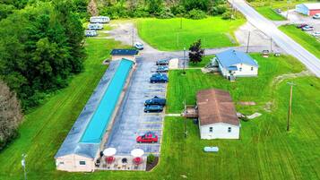 Vue aérienne d’un terrain de camping avec des camping-cars, une piscine et un petit bâtiment doté d’un espace extérieur aménagé pour s’asseoir.