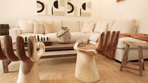 A living room with a sofa, wooden coffee table, and decorative chairs. - The Maya (Palm Springs)