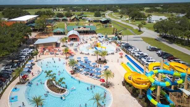 Ein Wasserpark mit großem Pool, Rutschen und einem Parkplatz.