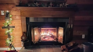A fireplace with a log fire, a red toy wagon, and a metal trash can. - Cabin. Hocking county ,private , secluded. Family, Friends. (Rockbridge)