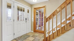 A hallway with a wooden staircase, a white door with glass panels, and a patterned doormat. - Cabin. Hocking county ,private , secluded. Family, Friends. (Rockbridge)