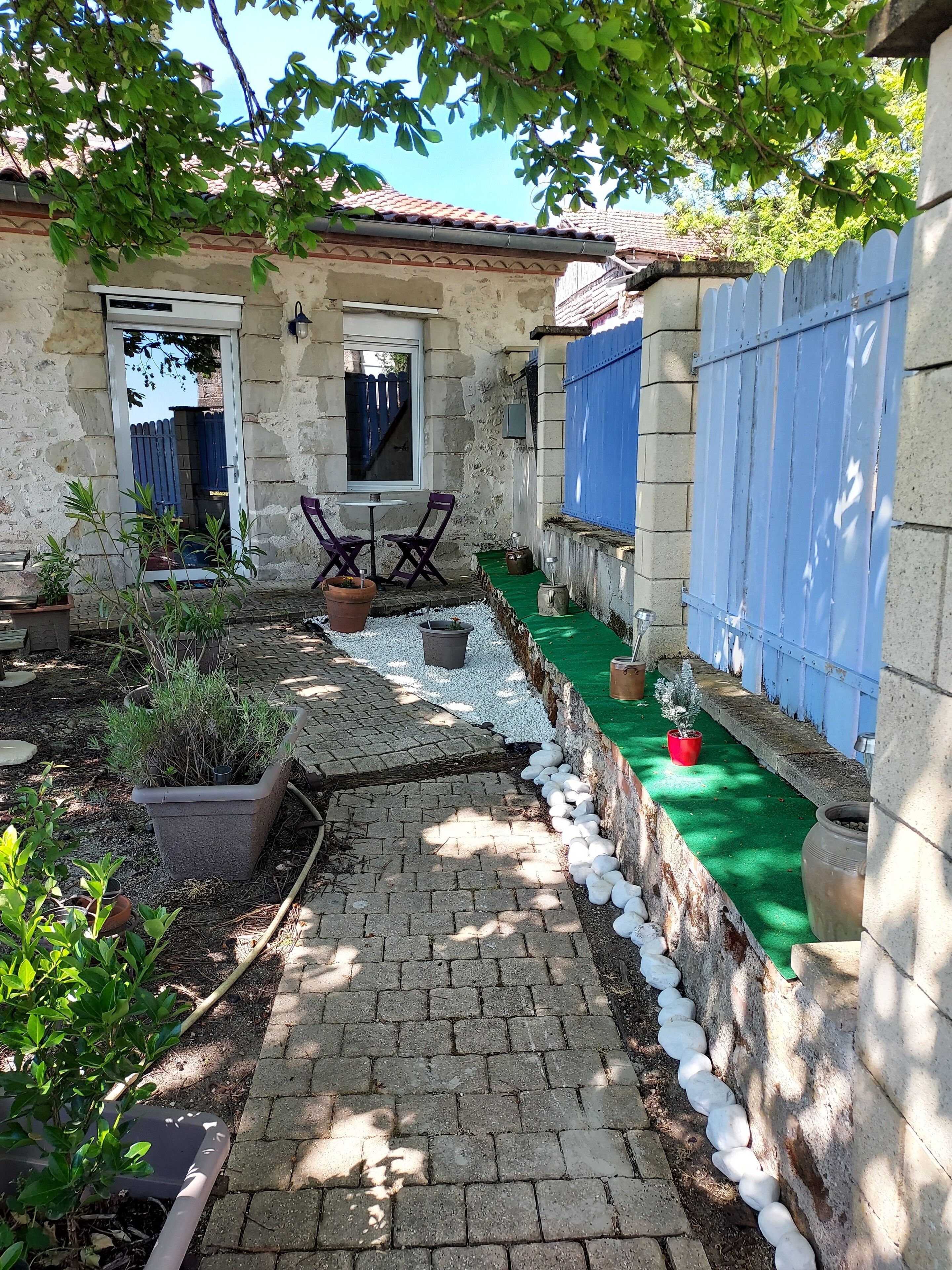 Una casa de piedra con un patio empedrado, mobiliario exterior y plantas en macetas.