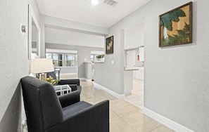 Enter a serene living space with a contemporary sofa, lamp, and large window offering a view of the outdoors.