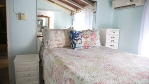 A bedroom with a bed, a dresser, a mirror, and an air conditioning unit. - Castle Cove-Ocean Front Villa (Negril)