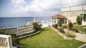 Un espace piscine avec vue sur la mer, des murs en pierre et un coin salon abrité.