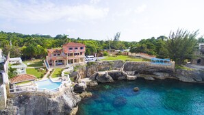 Un grand complexe hôtelier doté d’une piscine, de plusieurs bâtiments et d’une côte rocheuse.