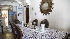 A dining area with a patterned tablecloth, wooden chairs, a chandelier, and a decorative mirror on the wall. - Castle Cove-Ocean Front Villa (Negril)