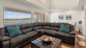 Ein modernes Wohnzimmer mit einer großen, ledernen L-Form-Couch, einem Couchtisch und Kunstwerken an den Wänden.