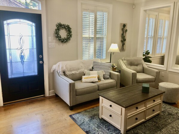 Un salon comprenant un canapé, un fauteuil, une table basse et une porte ornée d’une guirlande décorative.