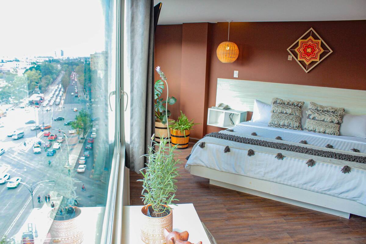 A bedroom with a large bed, a view of a city street, and a window with a view of the street.