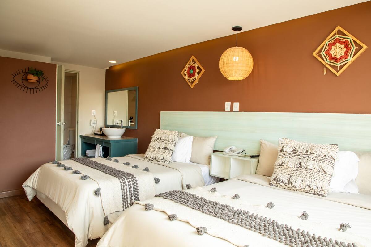 A hotel room with two beds, a bathroom, and a large mirror.