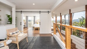 A spacious room with a large window, a wooden chair, a bed, and a view of the outdoors.