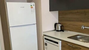 A compact kitchen with a white refrigerator, a dishwasher, and wooden cabinets. - Vanessa room (Orlando)