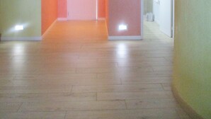 A hallway with a wooden floor, a door at the end, and a wall-mounted lamp. - Sunrise Beach Villas #2.. Oceanfront Villa (New Providence)