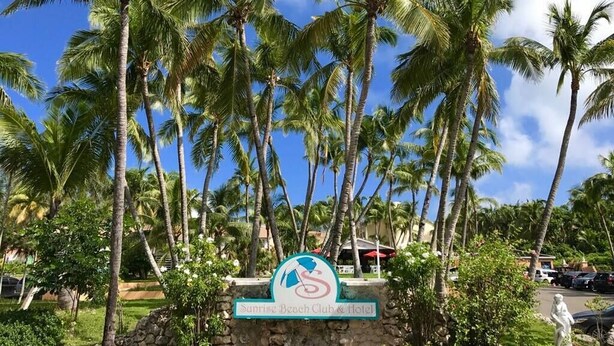 A sign for Sunrise Beach Club & Hotel surrounded by palm trees. - Sunrise Beach Villas #2.. Oceanfront Villa (New Providence)
