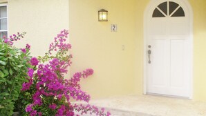 A yellow building with a white door and a number '2' sign. - Sunrise Beach Villas #2.. Oceanfront Villa (New Providence)