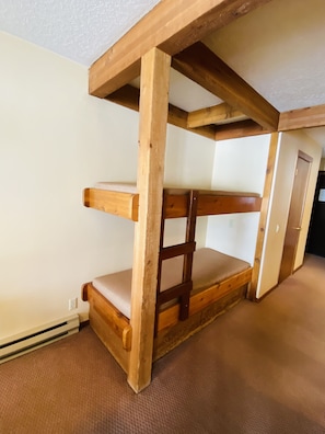 A bunk bed with wooden beams and a mattress.