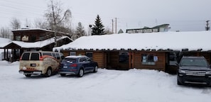 A wooden cabin with a sign for 'Nora's Fish Creek Inn' and a snow-covered roof.