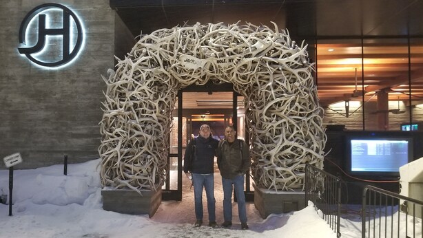 A hotel entrance with a large, illuminated logo, a sign indicating a connection to a nearby location, and a unique antler archway. - Available 1 week only: 
 Prime ski week Feb 22 - March 1 Sunday - Sunday (Wilson)