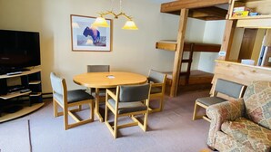 A cozy living room with a wooden dining table, chairs, a sofa, a TV, and a ceiling-mounted light fixture. - Available 1 week only: 
 Prime ski week Feb 22 - March 1 Sunday - Sunday (Wilson)