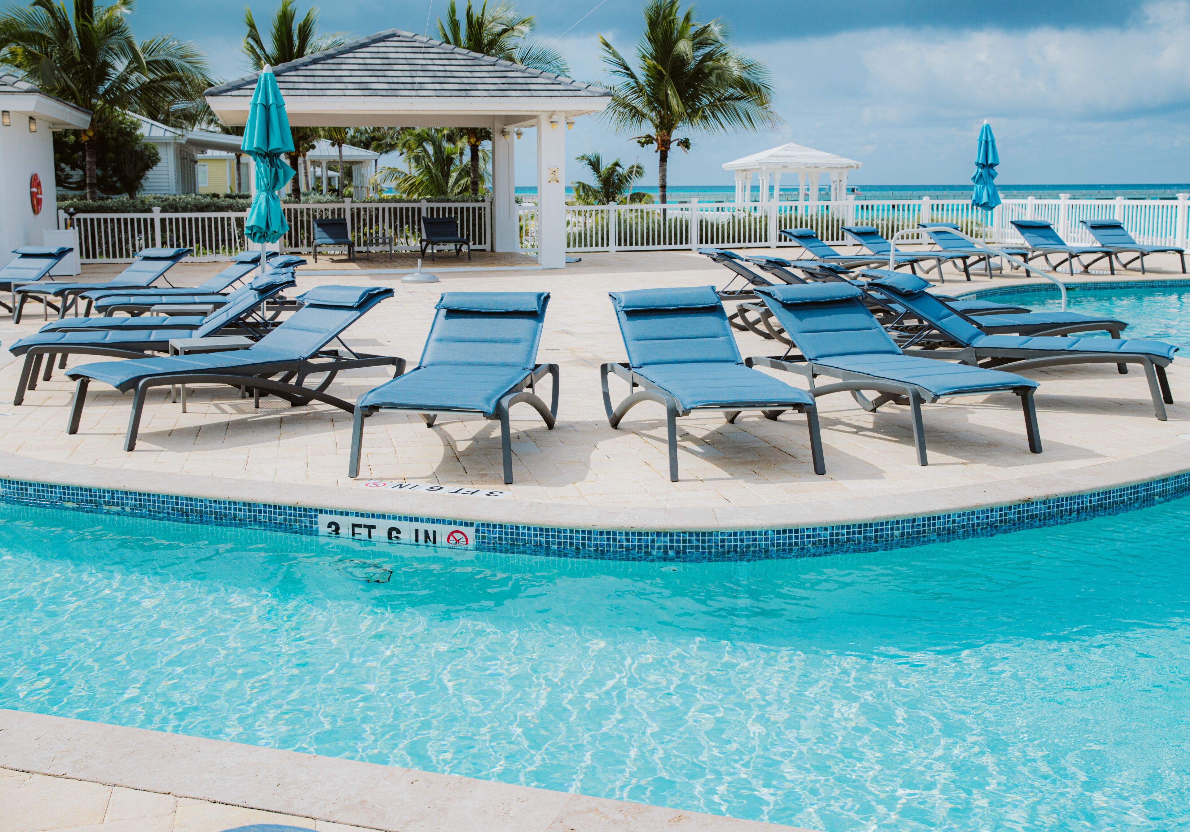 A poolside area with sun loungers, a gazebo, and a view of the ocean.