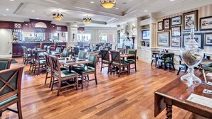 A spacious hotel lobby with wooden flooring, multiple dining areas with green upholstered chairs, chandeliers, and framed artwork on the walls. - Emerald Grande ❤️❤️ 7th Floor Corner Unit 😎😎 Wrap Around Balcony 🐠🐠 EV Chargers 🦀🦀 (Destin)
