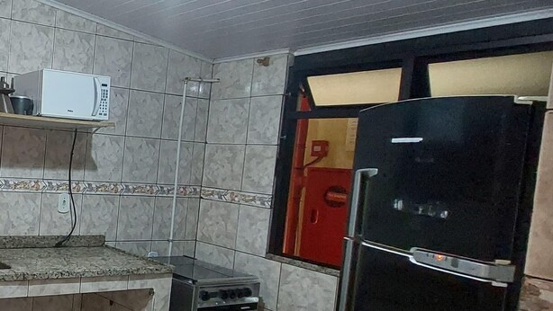 A kitchen with a microwave, a stove, and a refrigerator. - Arraial do Cabo - Apartment 04 - Brisas do Farol - Affordable Rental (Arraial do Cabo)