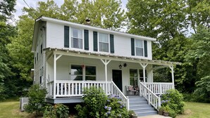 A two-story house with a porch, a front door, and a staircase leading to the entrance.