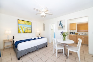Quarto de hotel com cama, escrivaninha, cadeira, mesa de jantar e cozinha.