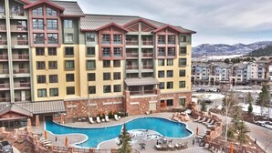 Ein mehrstöckiges Hotel mit Schwimmbad und Außenbereich zum Sitzen.